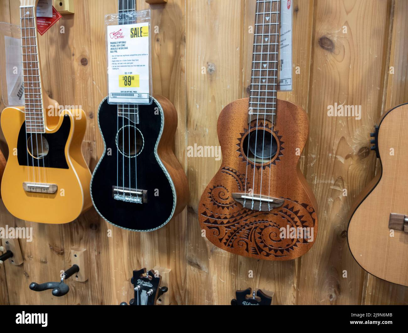Lynnwood, WA USA - circa maggio 2022: Primo piano, focus selettivo sugli ukulele in vendita sul muro all'interno di un negozio di strumenti musicali Guitar Center. Foto Stock