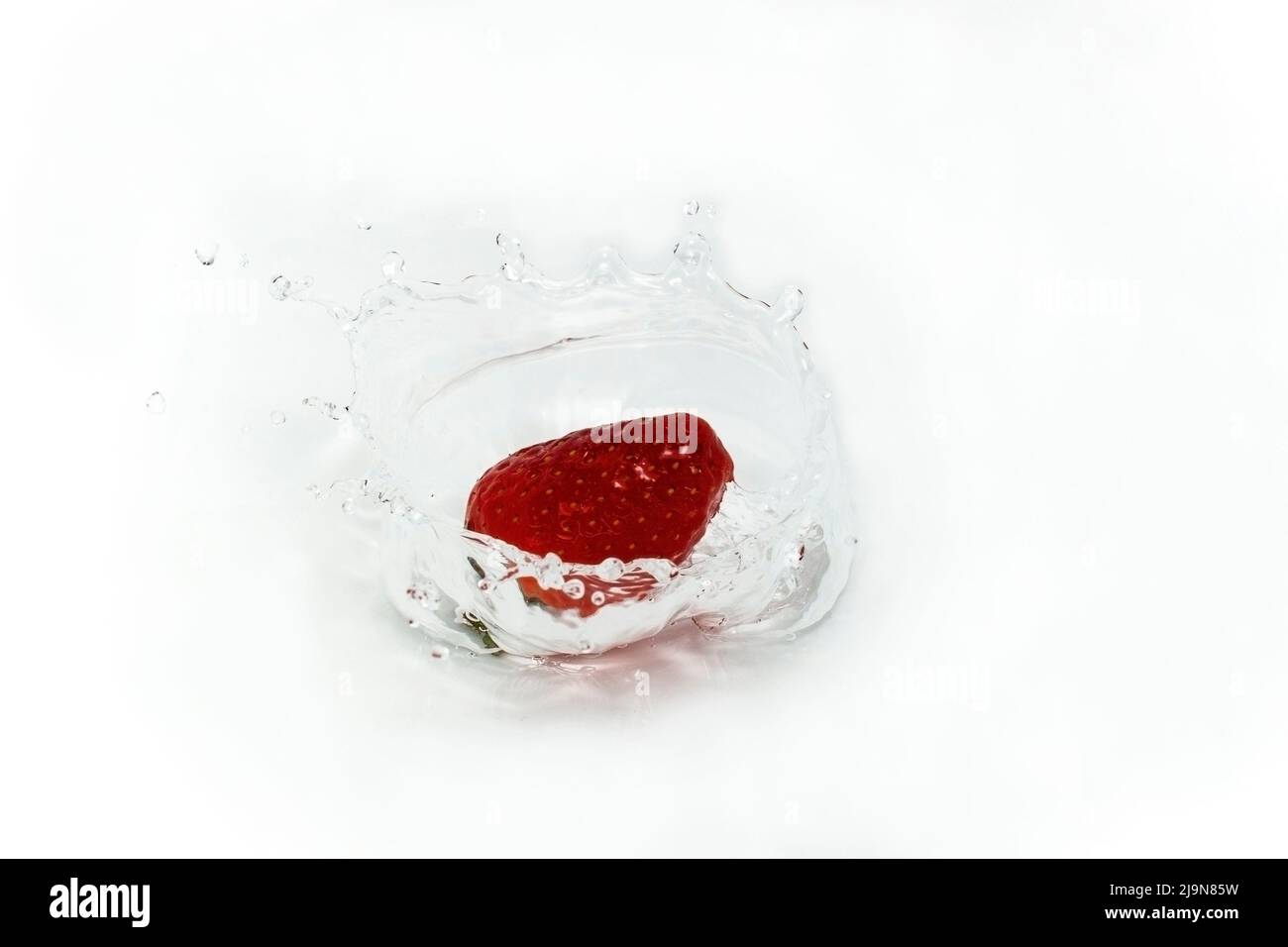 uno straberry spruzzi d'acqua su sfondo bianco , primo piano Foto Stock