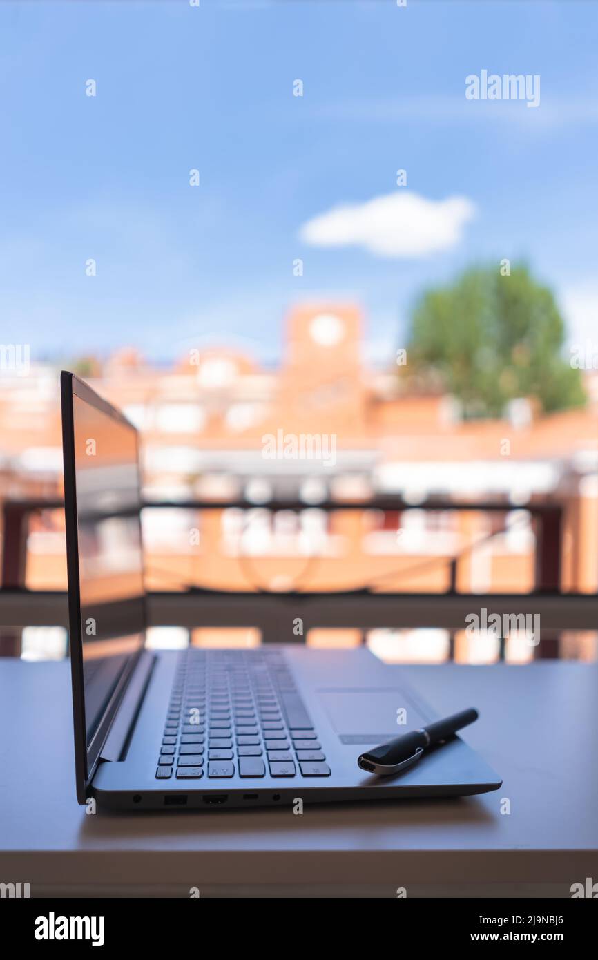 Computer portatile sulla terrazza preparato per telelavoro con belle viste della città. Foto Stock
