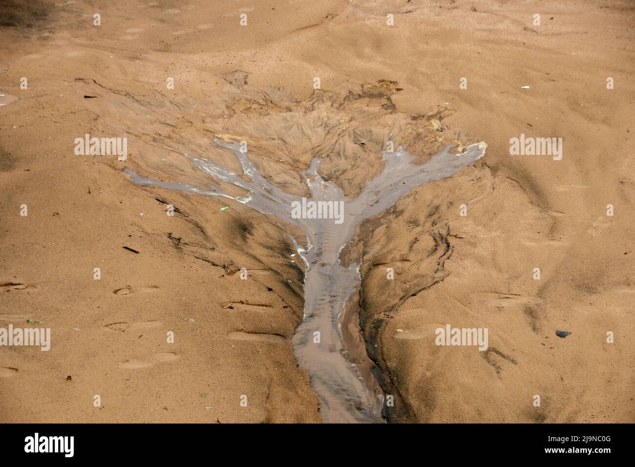 Una vista ravvicinata dell'acqua fluviale che scorre sulla spiaggia di sabbia dopo una tempesta. Foto Stock