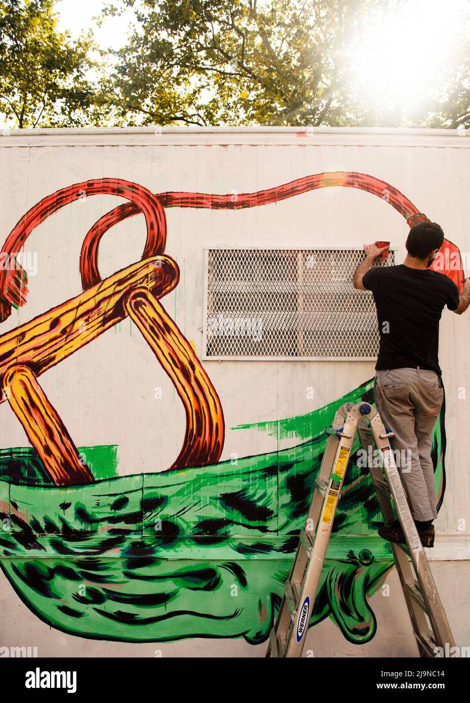 Uomo che dipinge un murale graffiti in Lower East Side Manhattan, New York City Foto Stock