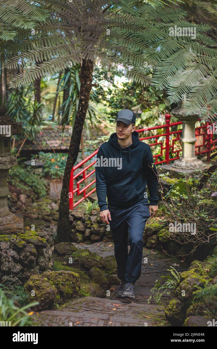 Avventuriero con il mantello nero cammina attraverso il giardino botanico di Monte Palace Madeira a Funchal, la capitale dell'isola portoghese. La bellezza del raro pla Foto Stock