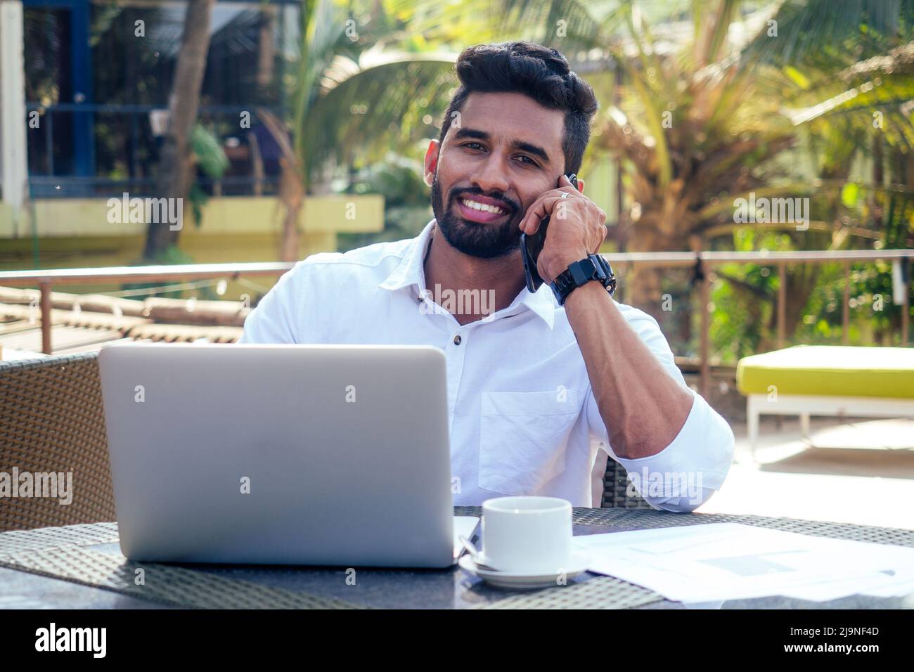 uomo che parla al telefono india estate holidays.stylish giovane uomo indiano freelancer lavorando con laptop freelance surf online.businessman a distanza Foto Stock