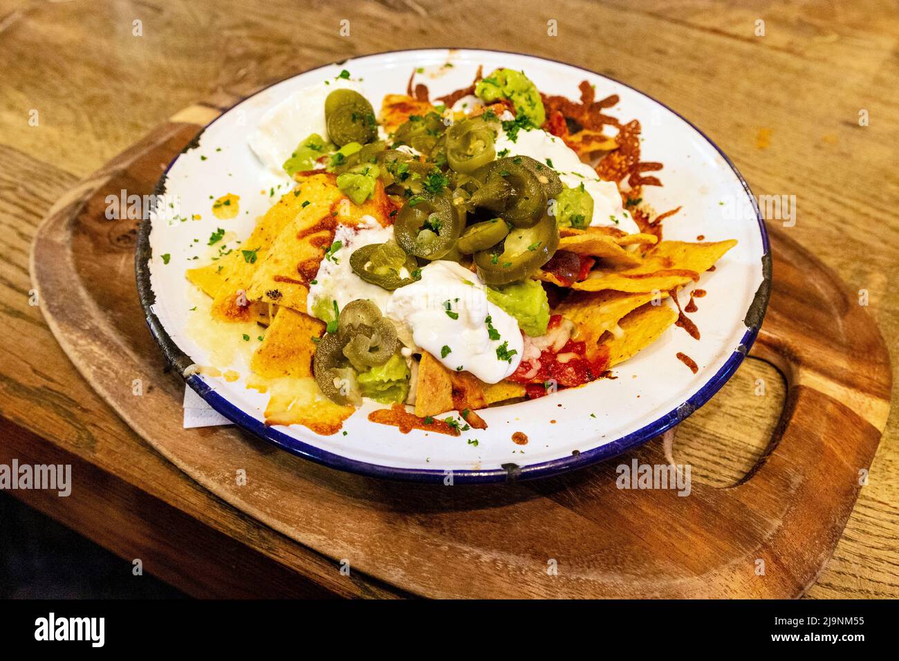 Al pub Old White Horse di Baldock, Hertfordshire, Regno Unito, è stato caricato Nachos con mozzarella, salsa, guacamole, jalapeños e panna acida Foto Stock