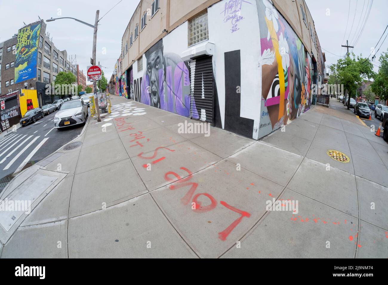 Una vista fisheye di un angolo a Bushwick, Brooklyn con Street art e un messaggio sul terreno che dice che l'amore è la risposta. Foto Stock