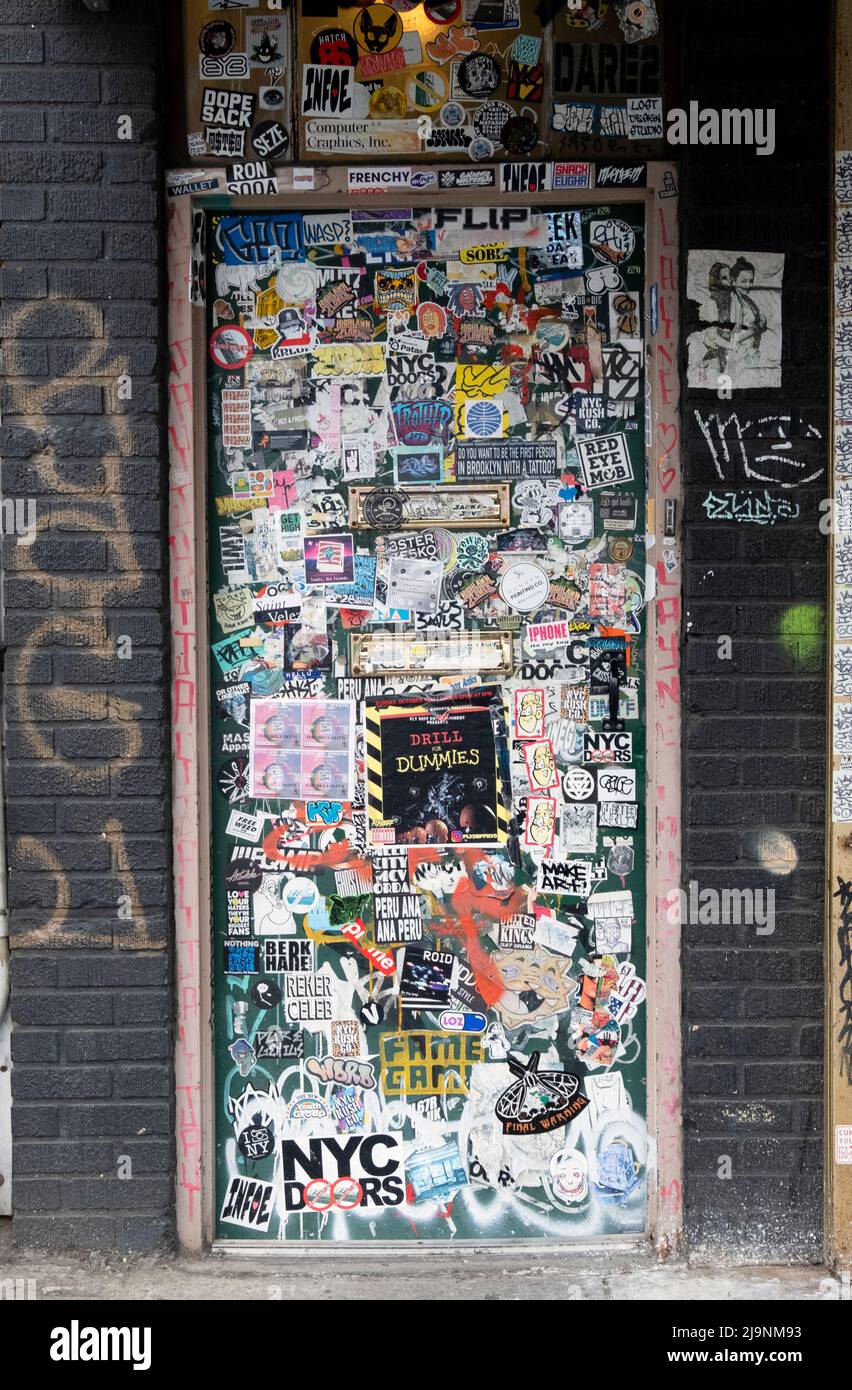 Una porta completamente coperta di adesivi, Street art, graffiti e tag. Su Wycoff Avenue a Bushwick, Brooklyn, New York Foto Stock