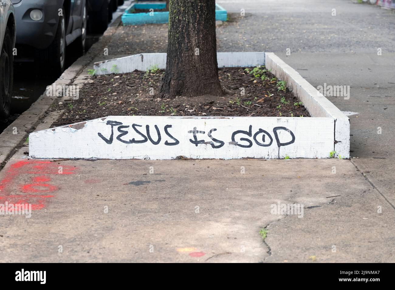 Gesù è Dio. Un messaggio religioso scritto su una lastra di legno a livello del suolo. Su una strada laterale a Bushwick, Booklyn, New York. Foto Stock
