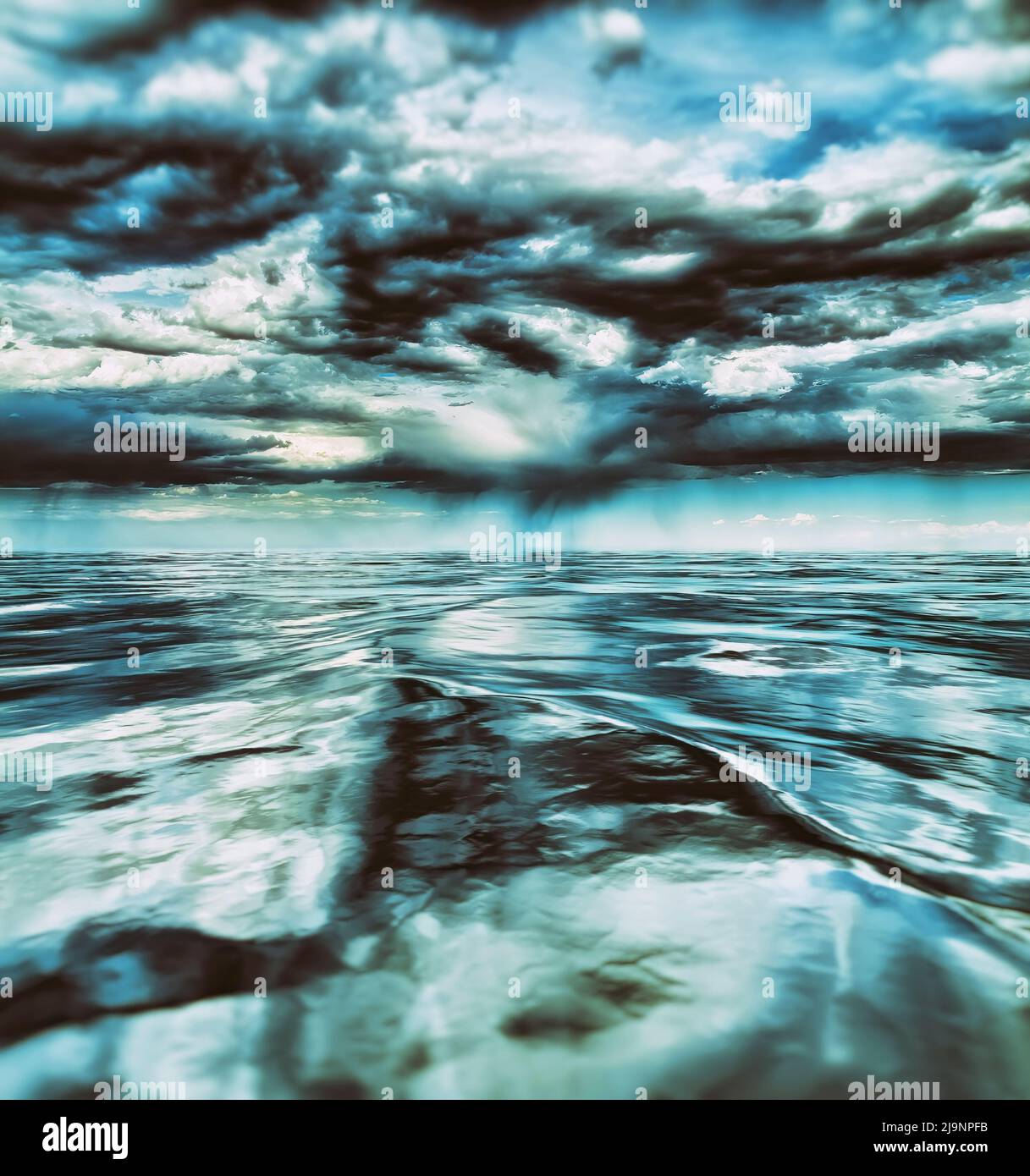 Un oceano freddo e tranquillo sotto nuvole di tempesta scure, che crea riflessi spettacolari sulla superficie dell'acqua Foto Stock