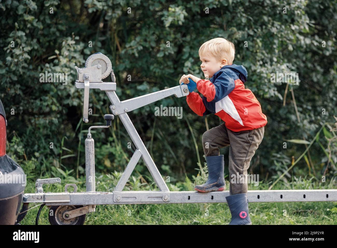 Un bambino agile si sport su un meccanismo di rimorchio di barca in natura. Foto Stock