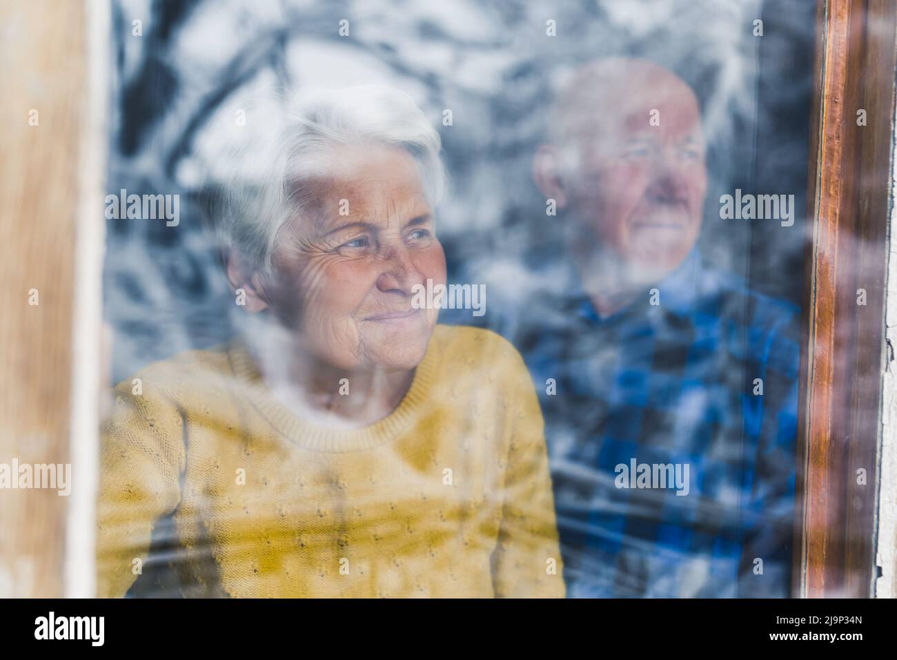 Amorevole coppia europea senior guardando attraverso la finestra a casa medio primo piano interno anzianità concetto. Foto di alta qualità Foto Stock