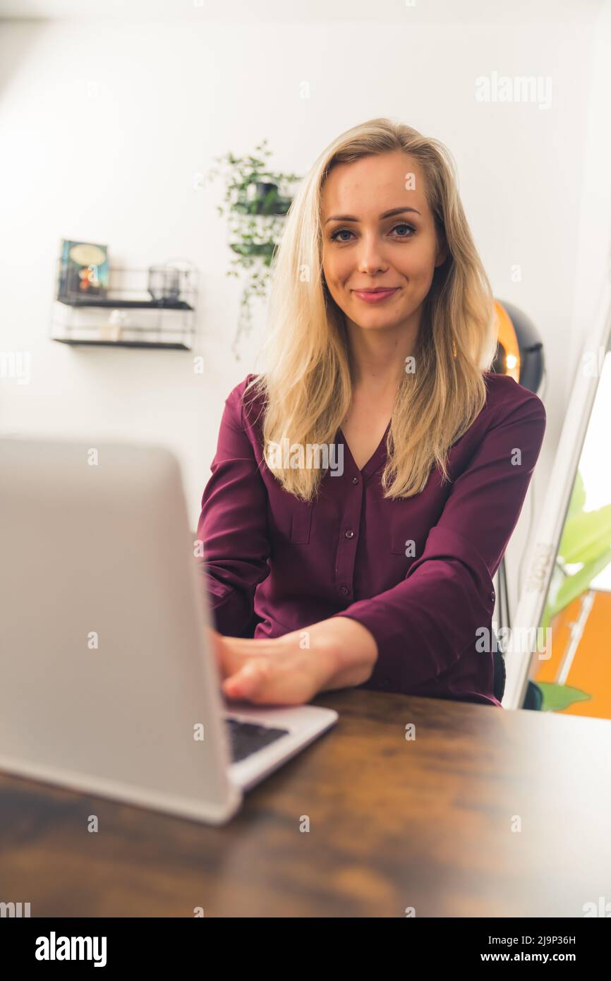 Ritratto di una bella donna seduta accanto al tavolo di fronte al laptop remoto concetto di copia spazio . Foto di alta qualità Foto Stock