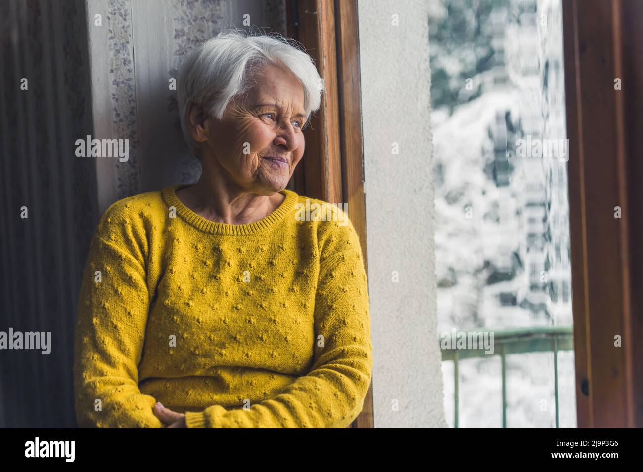 bella nonna guardando il suo nonno felice attraverso la finestra medio colpo coperta anzianità concetto. Foto di alta qualità Foto Stock