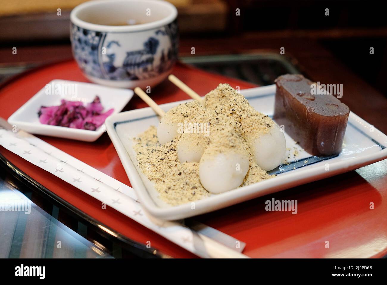 Un piatto di dolci tradizionali giapponesi - gelatina di fagioli rossi e palle di torta di riso con polvere di fagioli - servito con una tazza di hojicha Foto Stock