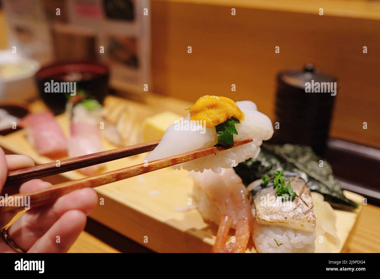 Un pezzo di ika nigiri con calamari crudi e uni (riccio di riccio di mare) in un ristorante Itamae sushi a Shinjuku, Tokyo Foto Stock
