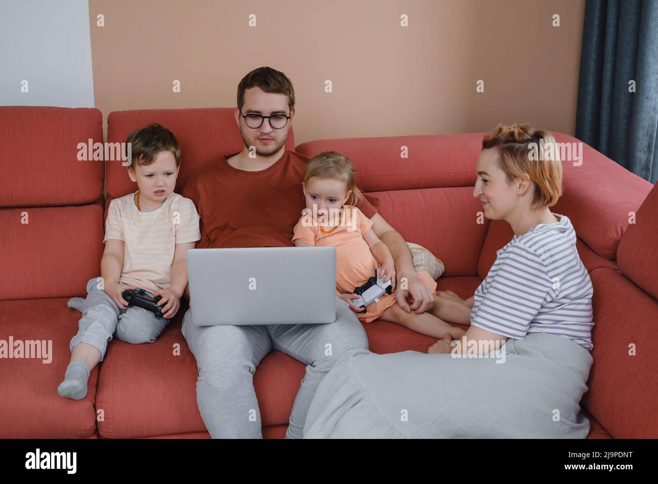 Grande famiglia felice di guardare film giocando a giochi su laptop. Madre padre bambini passare il tempo con gadget sul divano bambini con i genitori che cercano Foto Stock