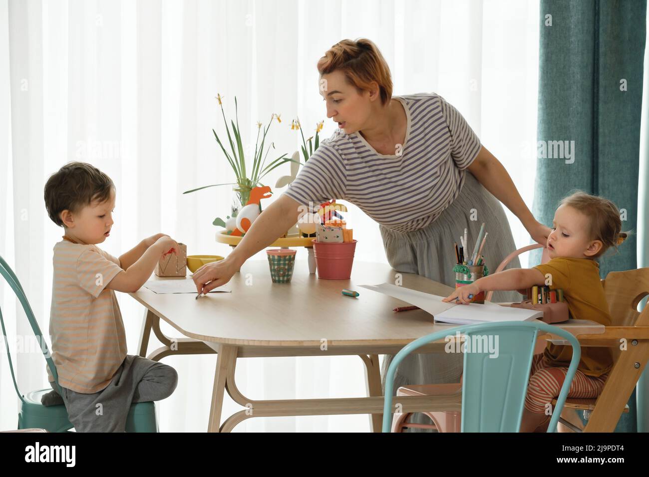 Famiglia con bambini divertirsi a casa al tavolo, creando arte fatta a mano. Madre e bambini disegnare e comunicare in cucina, emotivo Foto Stock