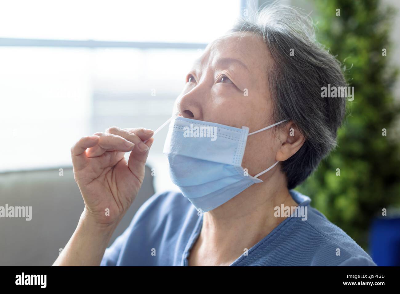 Donna anziana asiatica che fa auto-test per COVID-19 a casa con kit antigene. Foto Stock