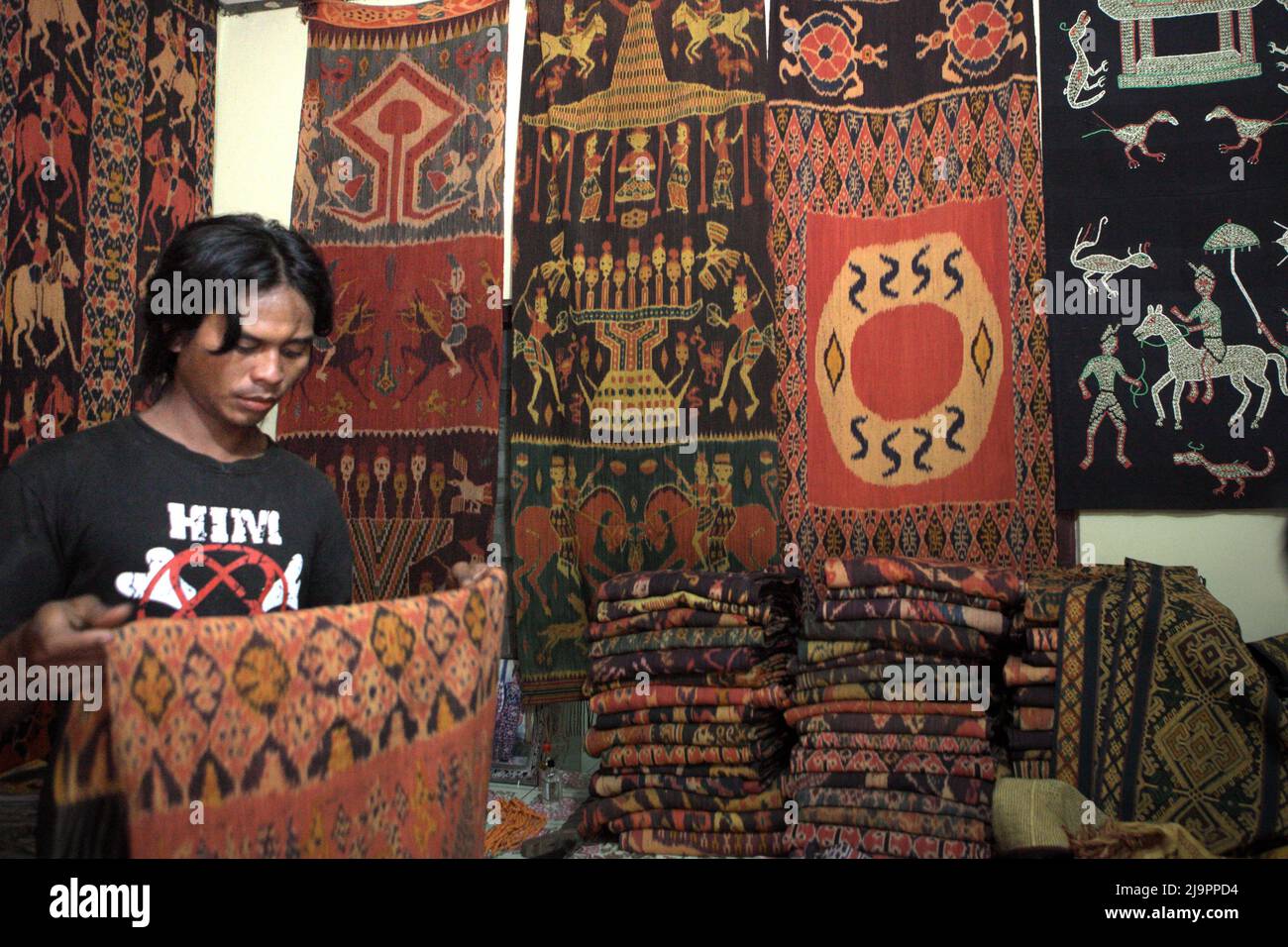 Un lavoratore che detiene un tessuto tradizionale Sumbanese in un negozio di tessuti a Waingapu, East Sumba, East Nusa Tenggara, Indonesia. Foto Stock