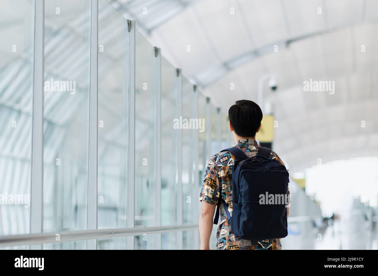Uomo asiatico con borsa in piedi e in attesa di viaggiare dopo la pandemia. Concetto di viaggio e vacanza. Foto Stock