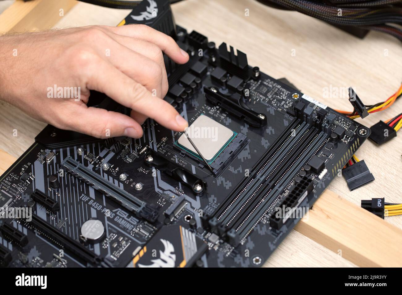 Primo piano di un uomo che installa il chip del processore del computer, microprocessore Ryzan. Hardware cpu del computer di manutenzione. Concetto di attività mineraria di criptovaluta. Russia, Foto Stock