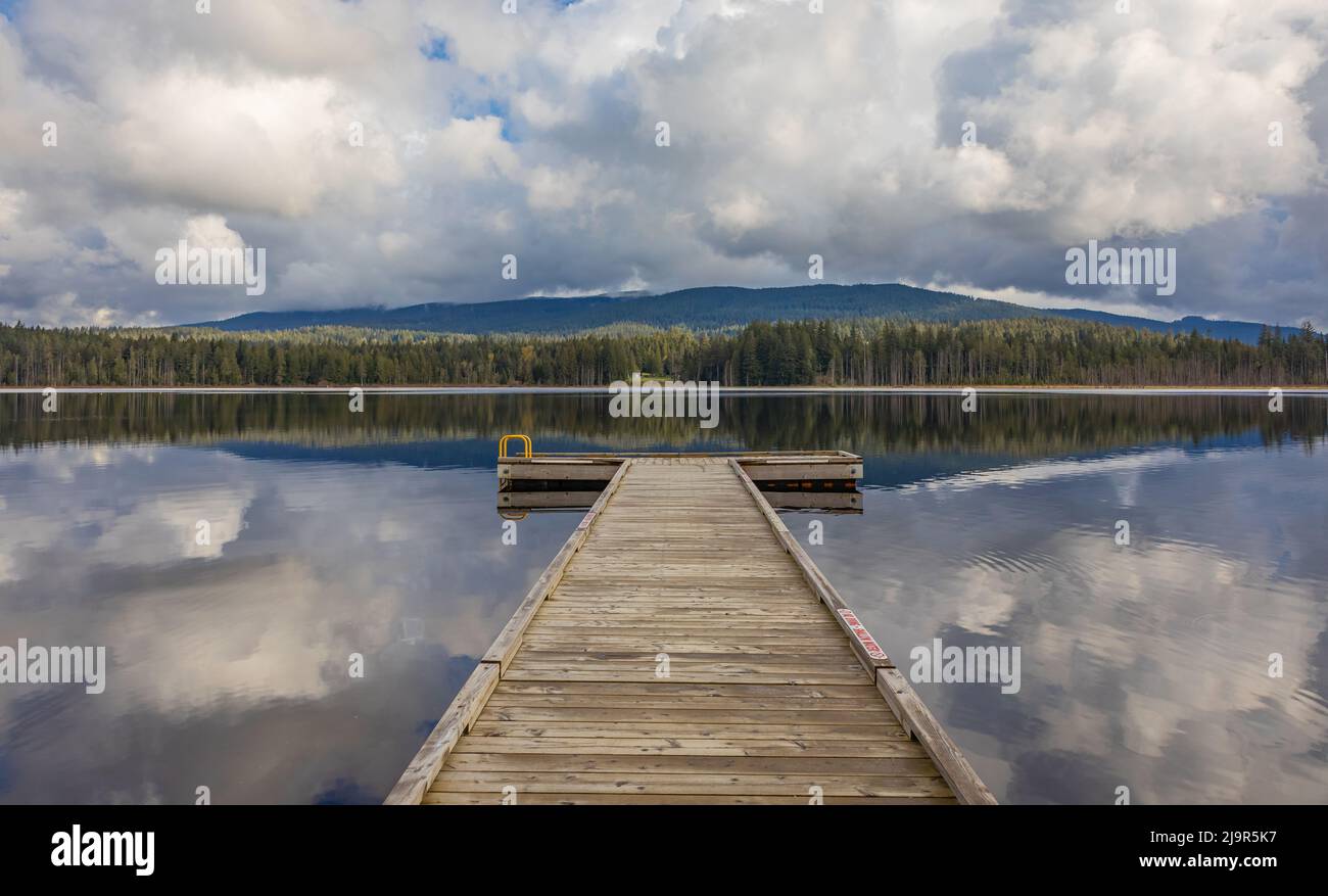 Vista idilliaca di un molo di legno nel lago con sfondo di montagna in mattina nuvoloso. Foto di viaggio, nessuno, fuoco selettivo. Foto Stock