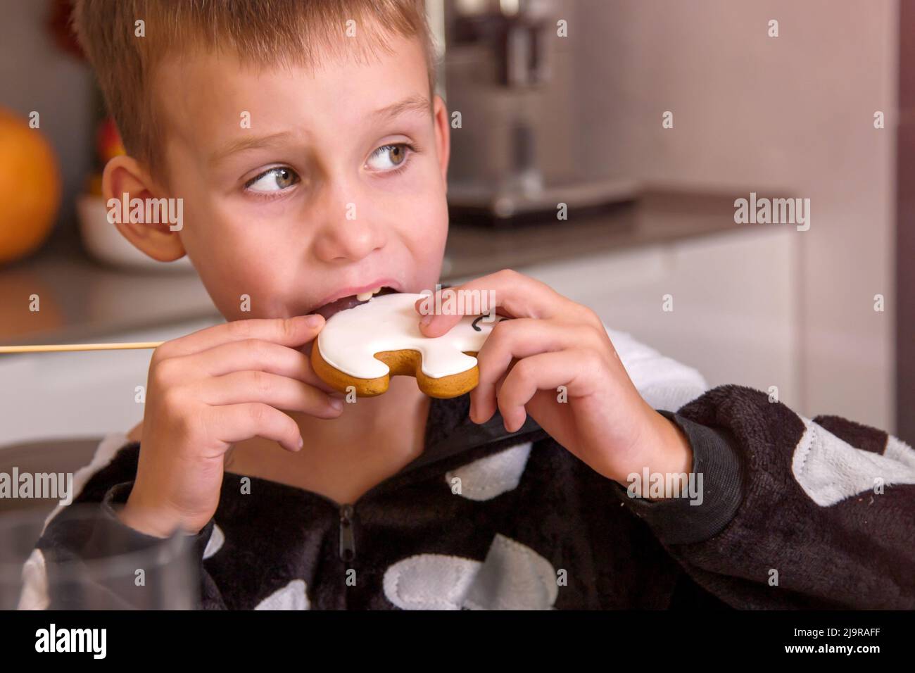 Ritratto di ragazzo in costume scheletro mangiare biscotti fatti in casa che assomiglia a fantasma Foto Stock