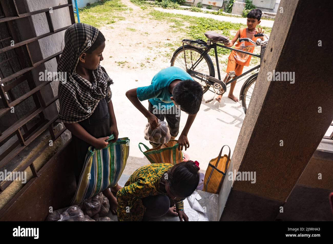 24 maggio 2022, Tehatta, Bengala Occidentale, India: Il governo del Bengala Occidentale ha diretto le scuole di governo di stato a distribuire le forniture di pasto di metà giorno ai genitori degli allievi durante le vacanze di estate in modo che i bambini bisognosi non siano privati del programma. L'avviso ha detto che ogni studente avrebbe ottenuto 2 kg di riso, 2 kg di patate, 250 grammi di zucchero, 250 grammi di legumi, e una saponetta. Così gli studenti sono venuti in una scuola elementare per ottenere i loro prodotti alimentari durante le vacanze estive e alcuni di loro stanno anche aiutando a dare gli articoli alimentari a Nabin Nagar, West Bengala. (Credit Image: © Soumrabyata Roy/Pacific Foto Stock