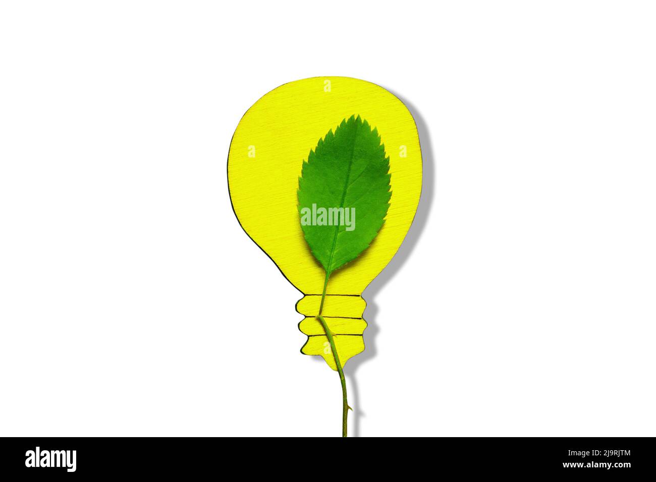 Lampadina piatta in legno a forma di giallo verniciato con una foglia verde sulla parte superiore isolata su bianco. Concetto di potenza alternativa. Foto Stock