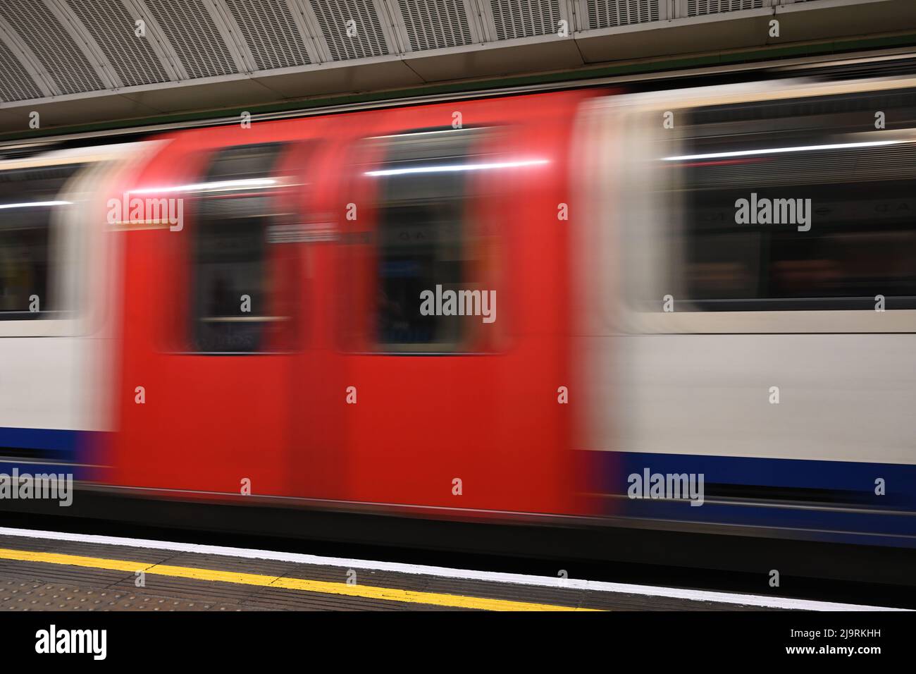 Una fotografia a bassa velocità dell'otturatore di un treno della metropolitana di Londra che passa attraverso la piattaforma fissa, mostrando il movimento del treno della metropolitana. Foto Stock