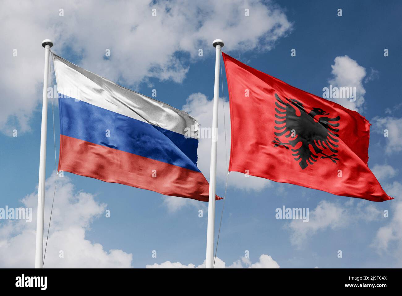 Russia e Albania due bandiere su flagpoli e sfondo blu cielo nuvoloso Foto Stock