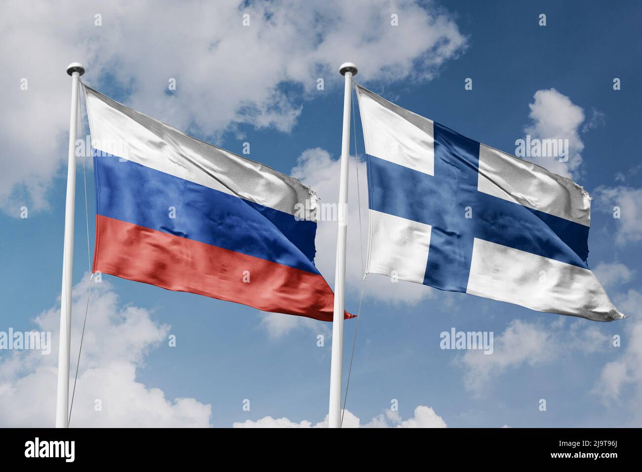 Russia e Finlandia due bandiere su flagpoli e sfondo blu cielo nuvoloso Foto Stock