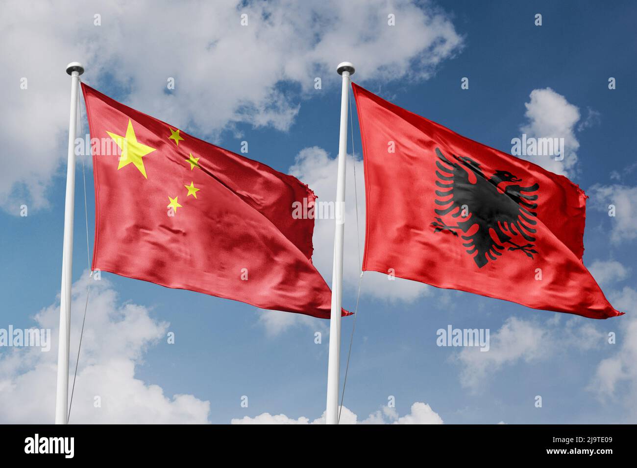 Cina e Albania due bandiere su flagpoli e sfondo blu cielo nuvoloso Foto Stock