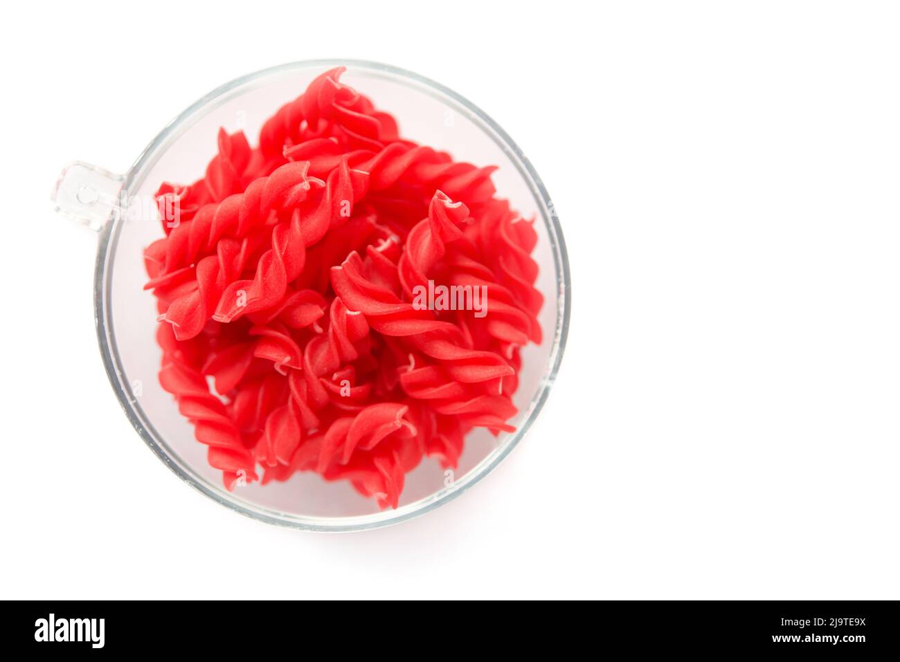 Primo piano sfondo di Fusille e Rotini in una ciotola di vetro su bianco. Pasta colorata Foto Stock