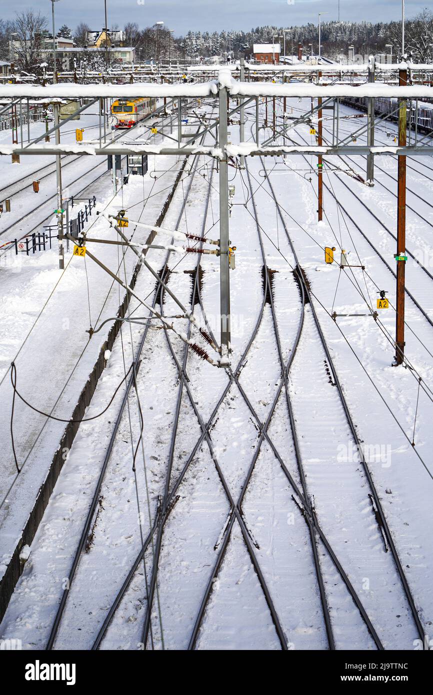 Paesaggio urbano invernale con vista su una linea ferroviaria multilinea con un treno elettrico in movimento in una giornata limpida e gelida. Foto Stock