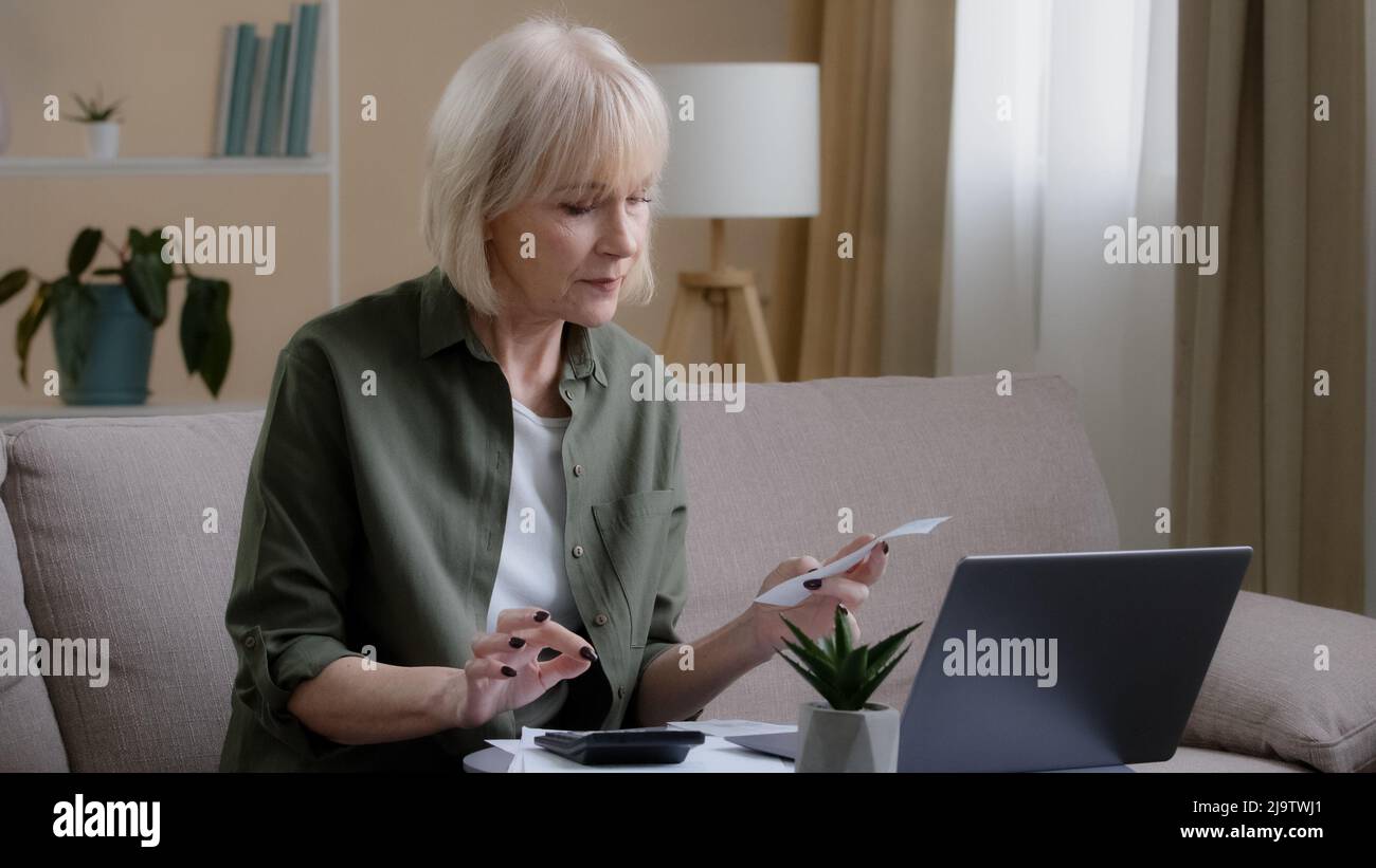 Grave caucasica vecchia donna anziana seduta sul divano controllo finanziario calcolo denaro bilancio fattura pagare con app online gestione delle finanze bancarie Foto Stock