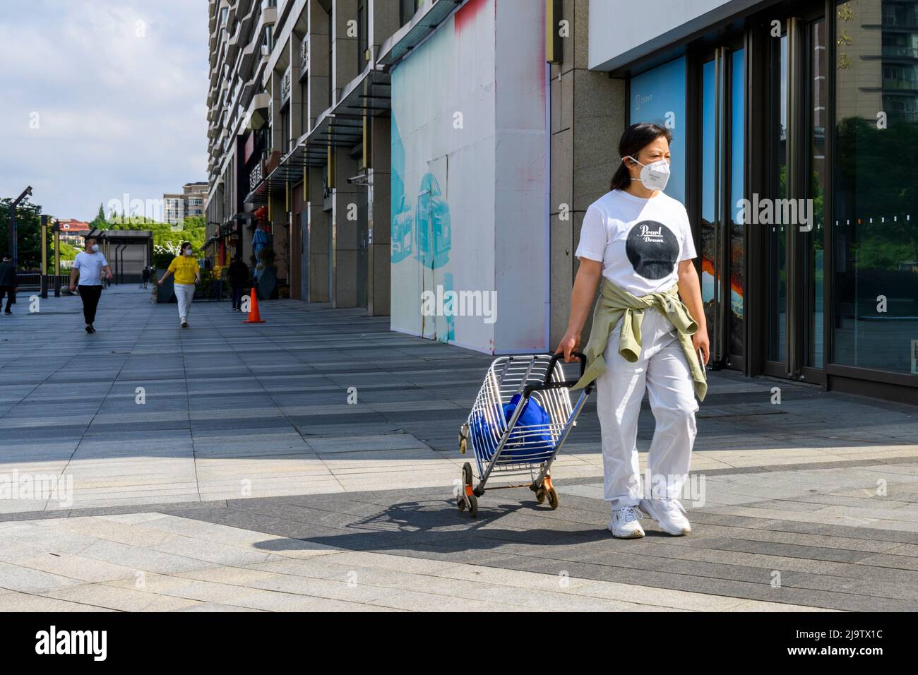 Un residente della città di Hongqiao tira il suo carrello di shopping prima di allinearsi per andare a fare shopping durante il blocco del coronavirus di Shanghai. Foto Stock