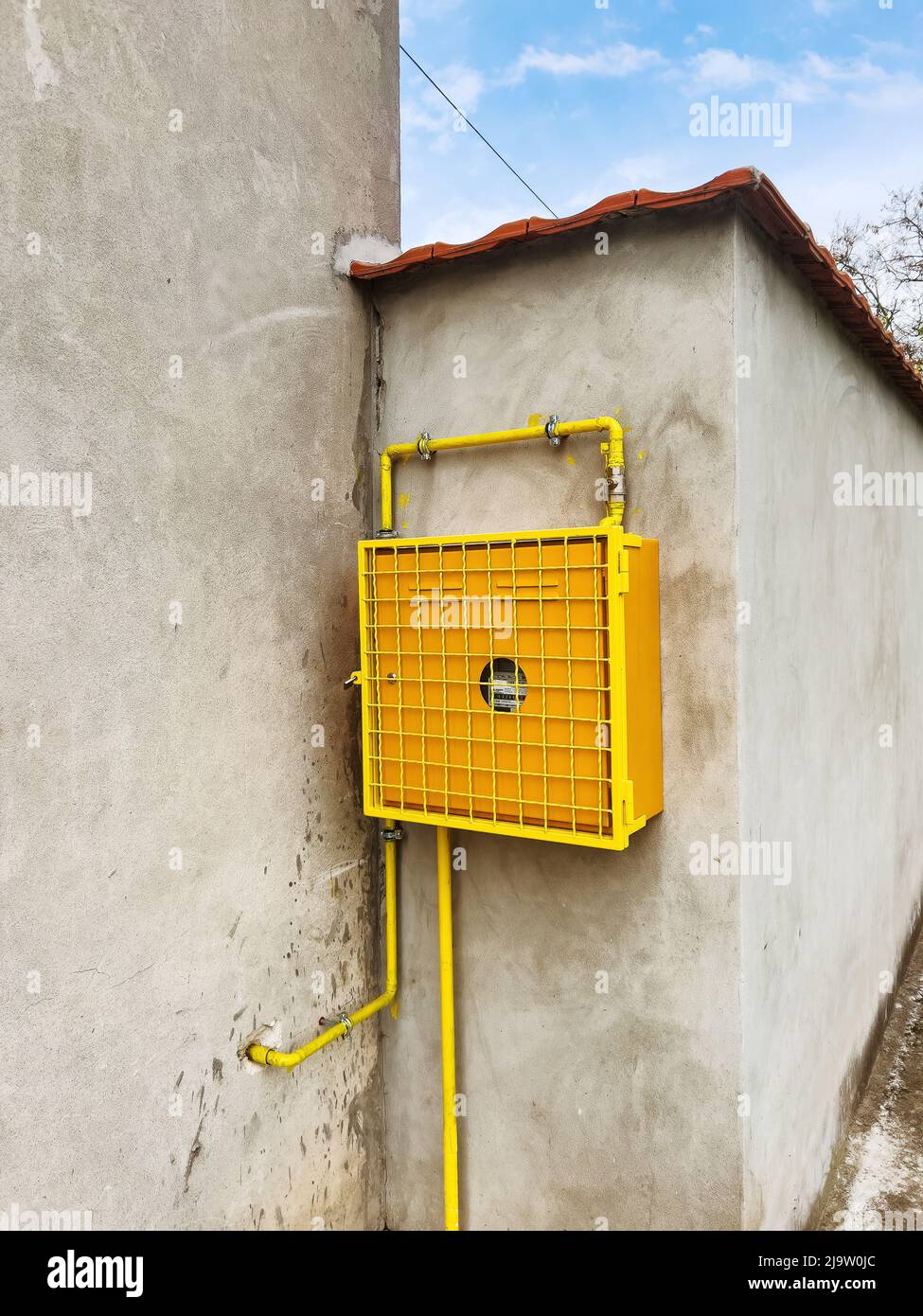 Misuratore di gas montato sulla parete della casa in involucro protettivo giallo Foto Stock