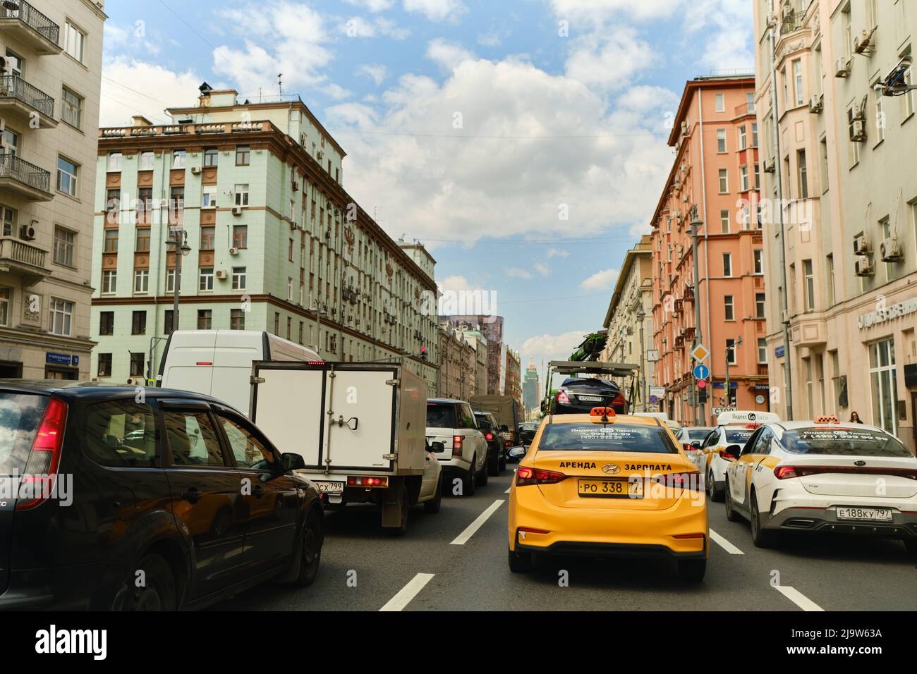 Mosca, Russia - 12 maggio 2022: Molte auto sono bloccate in ingorgo a causa del nuovo semaforo in via Tverskaya. Taxi, camion di traino, camion. Cielo blu Foto Stock