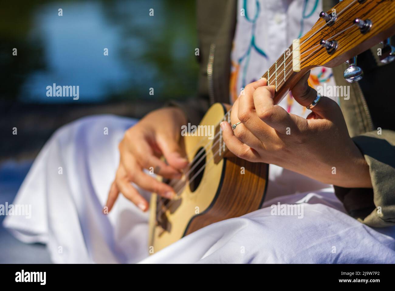 Donna che impara a giocare all'aperto ukulele. Divertimento di musica Foto Stock