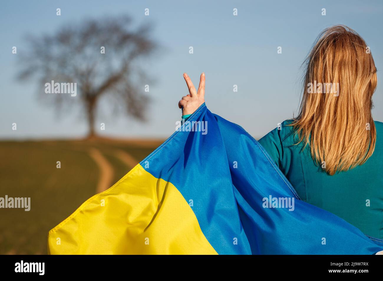 Donna con bandiera ucraina è mano gesturing pace o simbolo di vittoria. Foto Stock