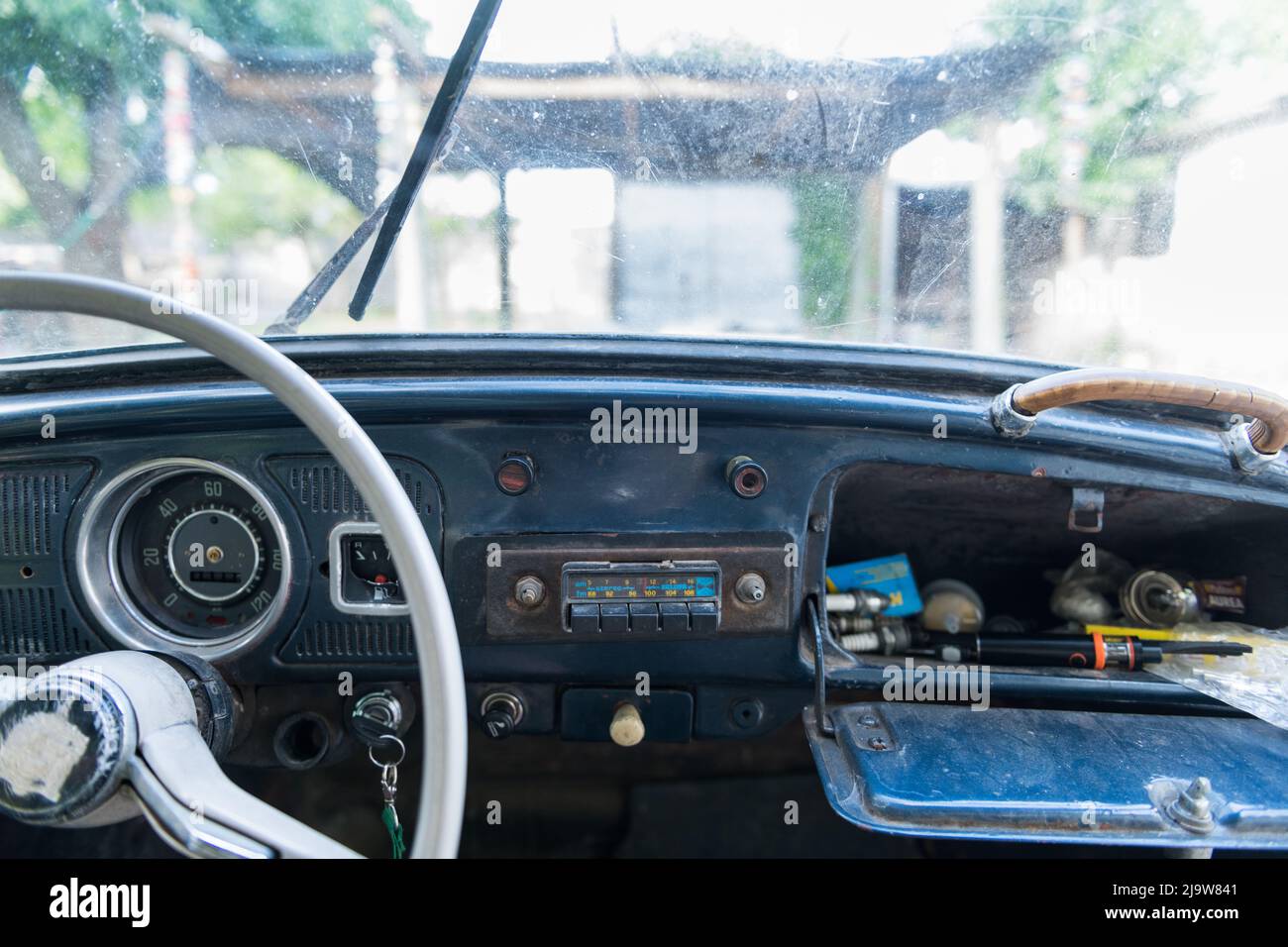 i dettagli del cruscotto di un vecchio scarabeo volkswagen dove il volante bianco e il vano portaoggetti dell'auto sono visibili in primo piano. Foto Stock
