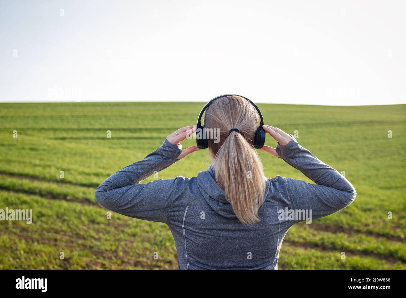 Donna con cuffie che si preparano per correre su strada. Jogging e attività fitness all'aperto Foto Stock