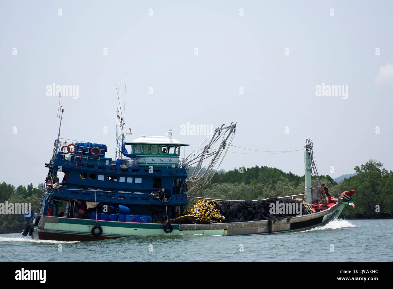 I pescatori thailandesi navigano in barca da pesca in mare dopo aver pescato i pesci e la vita marina nell'oceano di Mu Ko Phetra Marine National Park fino alla spiaggia di Pa Foto Stock