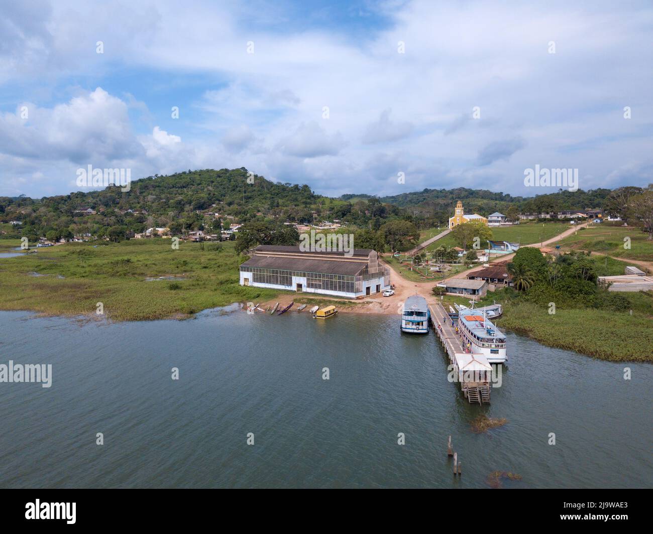 Vista aerea di Drone dello skyline della città di Fordlandia nella foresta pluviale amazzonica, Brasile. Il fiume TAPAJOS e la storica torre del serbatoio d'acqua. Barche in legno in riva al fiume. Foto Stock