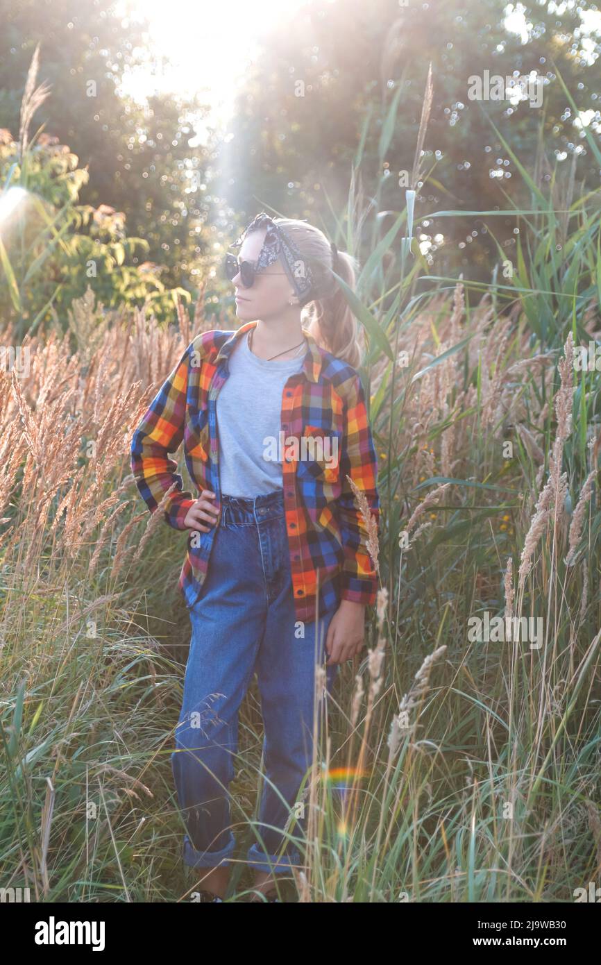 Defocus teen o ragazza di età preteen a piedi sulla natura sfondo. Bambina piccola che tiene mazzo di pampas erba. Prato verde, campo. Generazione z. Posa. R Foto Stock