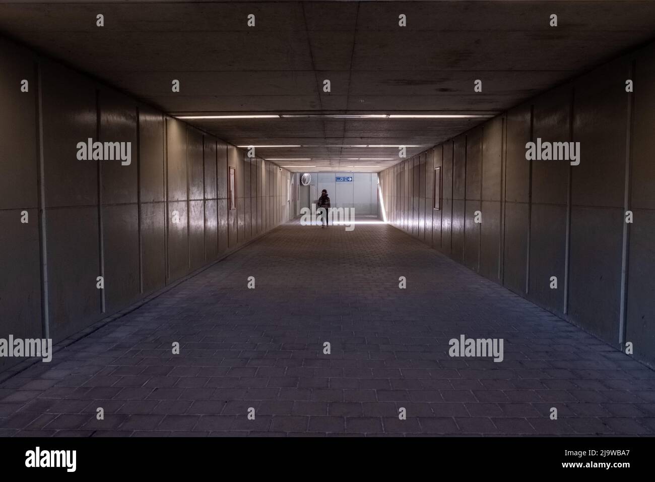 La donna cammina lungo il tunnel verso la luce. Silhouette di una donna che cammina nel sottopasso. Foto di alta qualità Foto Stock