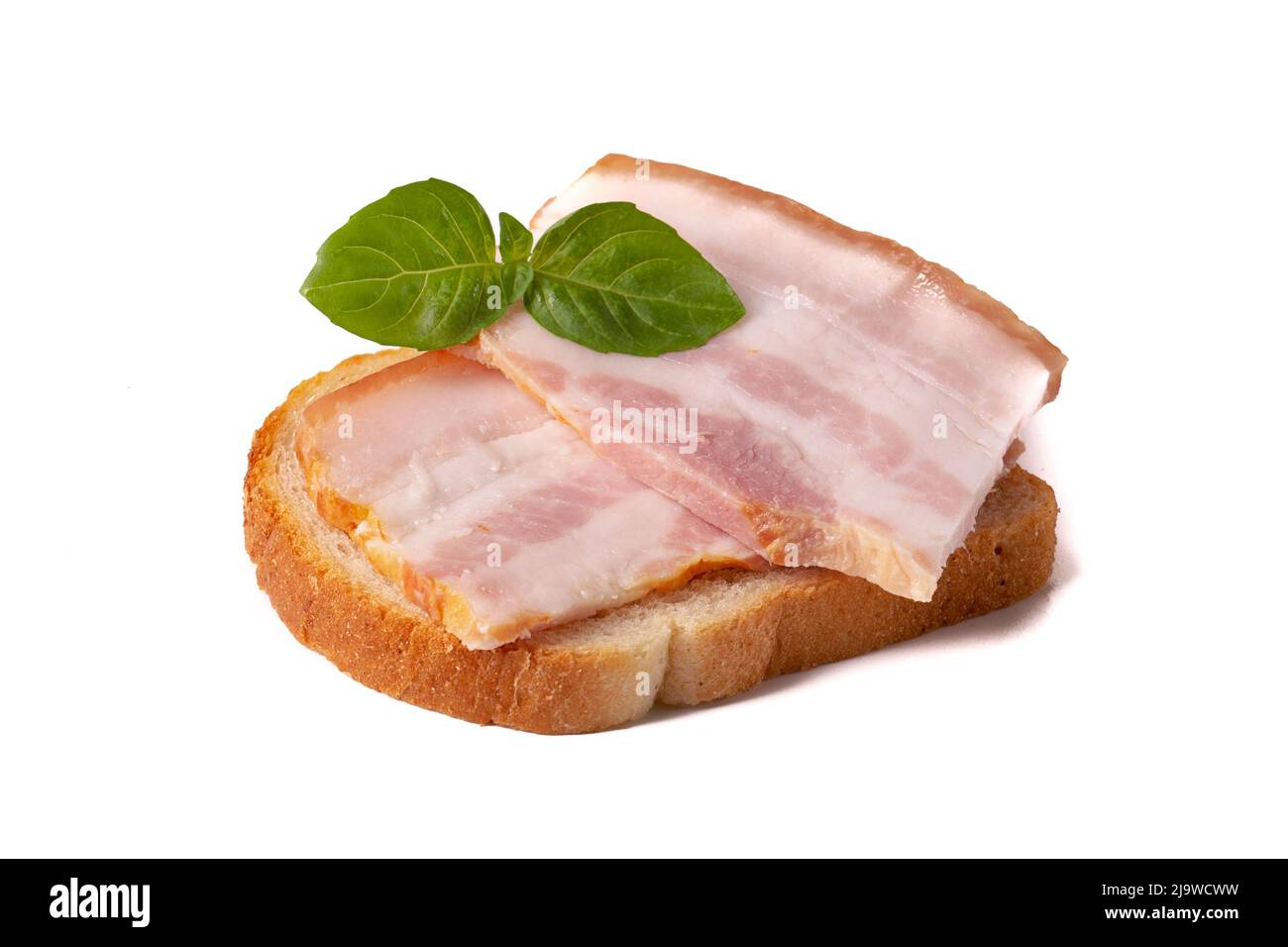 Un pezzo grezzo di pancetta fresca con una foglia di basilico verde su un pezzo di pane bianco di grano isolato su sfondo bianco. Foto Stock