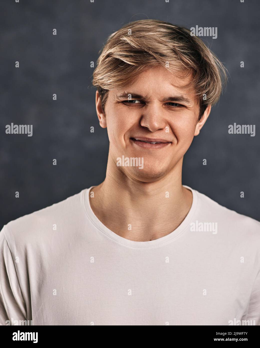 giovane uomo accigliato su sfondo grigio. Emozioni umane Foto Stock