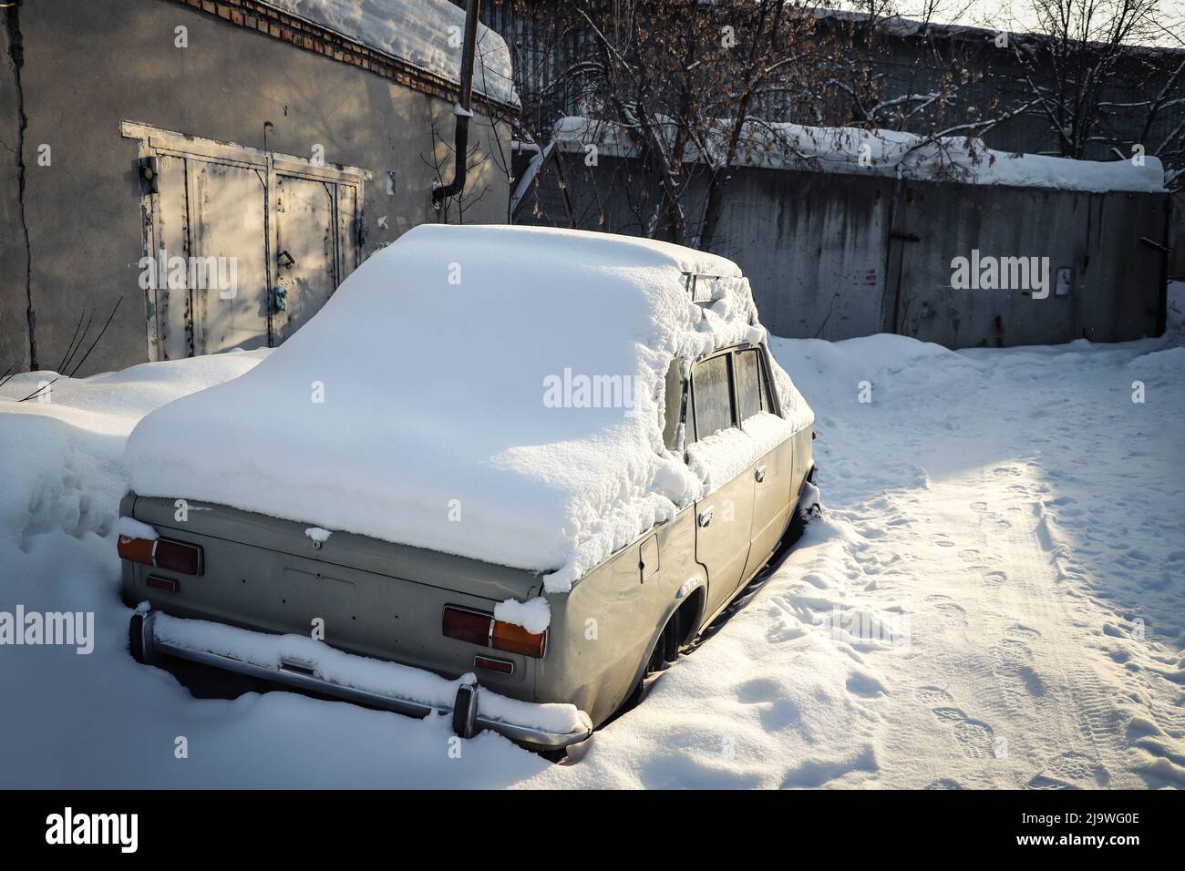 Nevicate su una vecchia auto abbandonata in zona industriale. Inverno. Specifico per la stagione. All'aperto Foto Stock