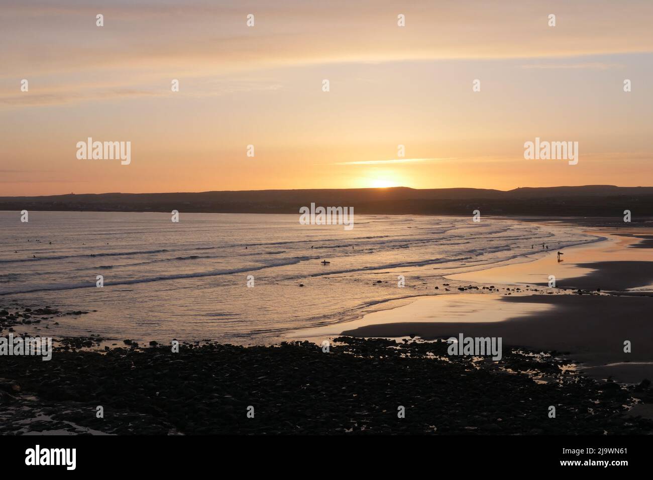 Il sole che scende sul bordo occidentale. Il sole tramonta e surfisti a Lahinch, nella parte occidentale dell'Irlanda. Foto Stock